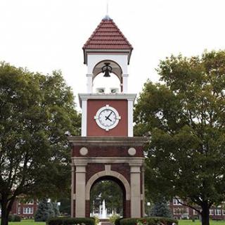 A classic brick clock tower surrounded by trees.