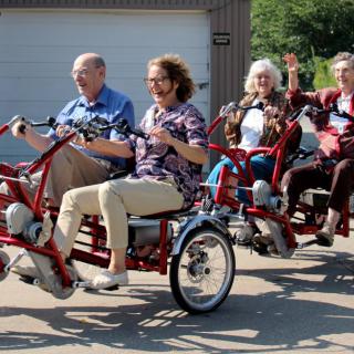 A group of people enjoying a ride on a multi-seat bicycle outdoors.