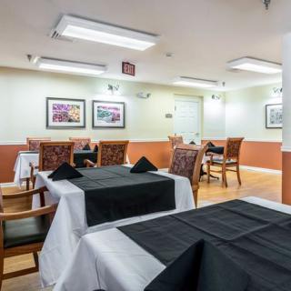 A neatly arranged dining area with black tablecloths and framed art on the walls.