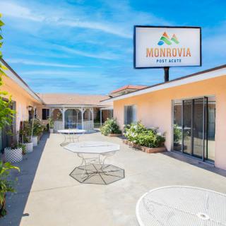 A sunny courtyard area of a motel with outdoor tables and a visible motel sign.