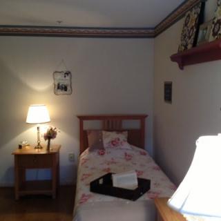 A cozy bedroom with a single bed, nightstand, and warm lighting.