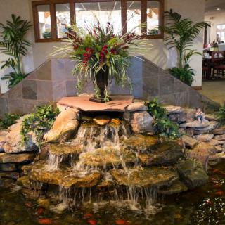 An elegant indoor waterfall feature with cascading water over rocks, surrounded by lush plants.