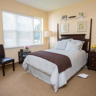 A neatly arranged bedroom with a bed, nightstands, and a lamp.