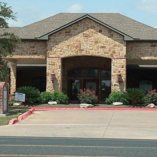 A brick building with a prominent entrance and landscaped surroundings.