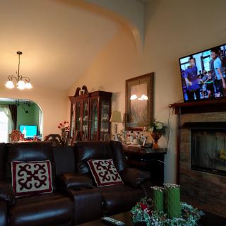 A cozy living room with a leather sofa, fireplace, and wall-mounted television, adjacent to a dining area.