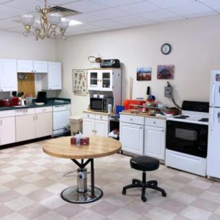 A kitchen with appliances, cabinets, a table, and a chair.