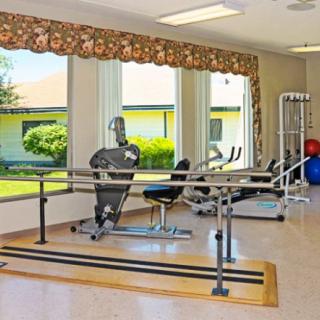 A rehabilitation room with therapy equipment and large windows.