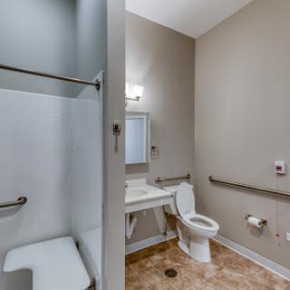 A spacious and accessible bathroom featuring a shower, toilet, and sink.