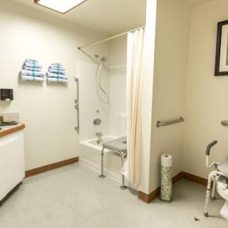 An accessible bathroom designed for individuals with mobility challenges, featuring safety bars and a shower bench.