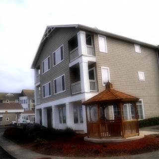 A view of a three-story residential building with a wooden gazebo in the foreground.