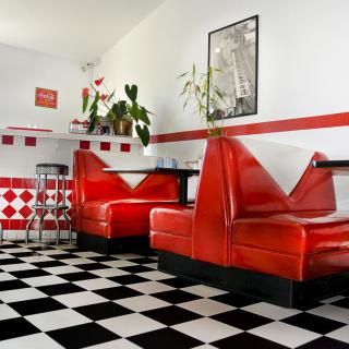 A retro diner interior with red booths and a classic black and white checkered floor.