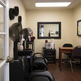 An interior view of a salon with chairs, a mirror, and hair dryers.