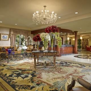 A luxurious hotel lobby with elegant decor, featuring a grand chandelier and floral arrangements.