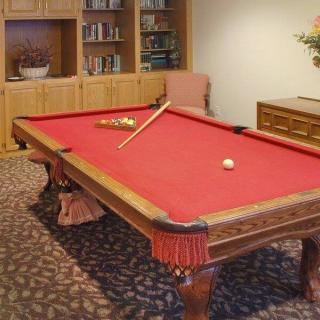 A cozy game room featuring a pool table with red felt and a cue stick resting on top.
