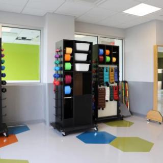 A therapy room equipped with colorful exercise equipment and tools.