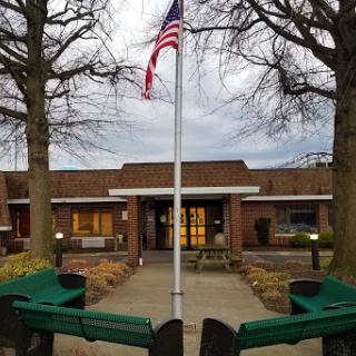 A view of a building featuring an American flag and surrounding trees.