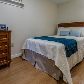 A cozy bedroom with a neatly made bed and a wooden dresser.