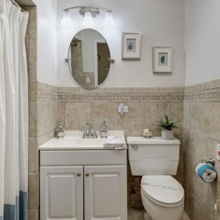 A small, neatly arranged bathroom with a toilet, vanity sink, and shower area.