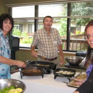 A group of people cooking food indoors at a gathering.