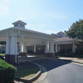 A building entrance with a covered driveway and columns on a sunny day.