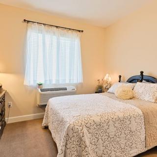 A cozy bedroom with a bed, lamp, and window offering natural light.