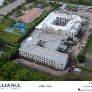 Aerial view of a construction site with a large building and adjacent tennis courts.