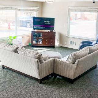 A cozy living room with a large sectional sofa, TV, and abundant natural light from large windows.