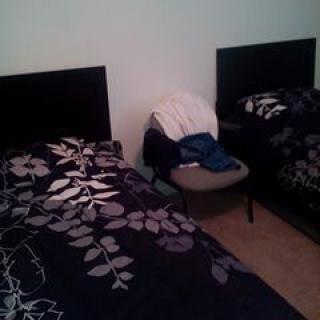 A bedroom with twin beds and floral bedding, featuring a chair between them.