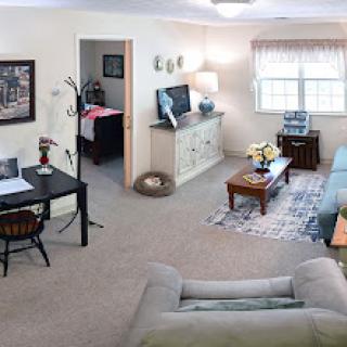A cozy living room featuring a desk, sofa, and television.