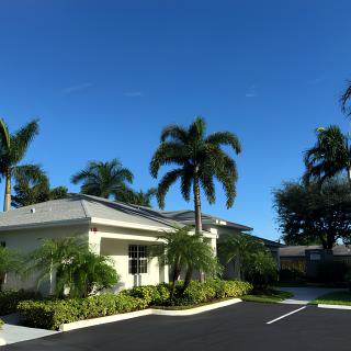 A suburban building surrounded by palm trees under a clear blue sky.