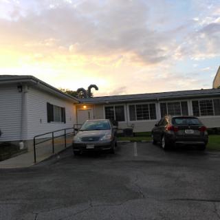 Evening view of a residential building with parked cars and a beautiful sky.