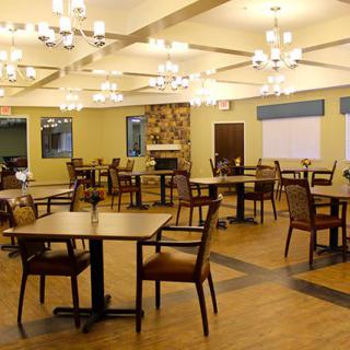 Elegant dining area with neatly arranged tables and chairs, enhanced by warm overhead lighting.
