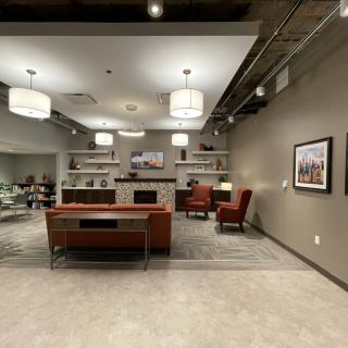 A modern office reception area with a desk, comfortable seating, and stylish lighting.