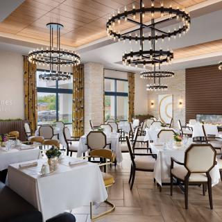 Elegant restaurant dining area with chandeliers and white tablecloths.