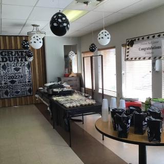 A room decorated for a celebration, featuring black and white themed balloons and a congratulatory banner.