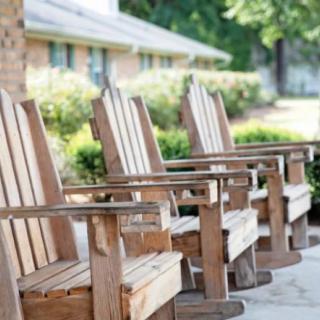 A row of wooden chairs on a patio, perfect for enjoying a sunny day in the garden.