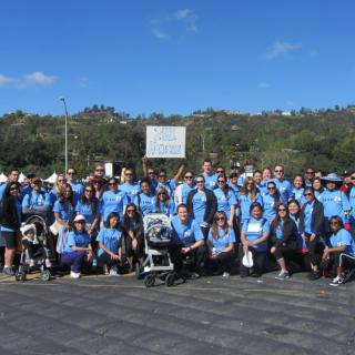 A large group of people wearing blue shirts gathered outdoors for an event.