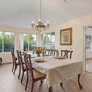 A well-lit dining room with a large table, multiple chairs, and a chandelier.