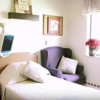 A cozy hospital room with a bed and an armchair near the window.