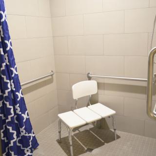 An accessible shower with a chair and grab bars for safety.