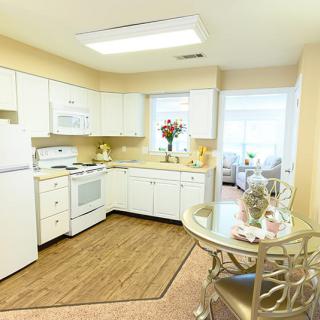 A modern kitchen with white cabinets, a dining area, and bright lighting.