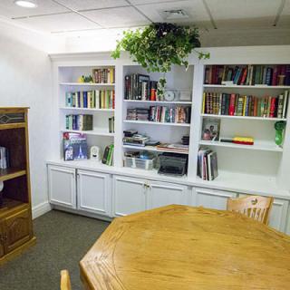 A cozy library corner with a wooden table and a well-stocked bookshelf.