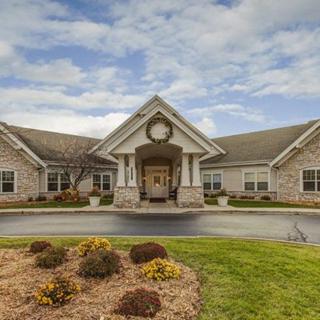 A residential building with a landscaped front, featuring a circular driveway and a cloudy sky.