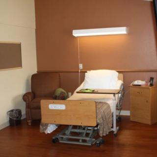 A hospital room with a patient bed, couch, and bedside table.
