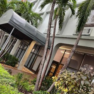 A modern building entrance framed by lush palm trees.