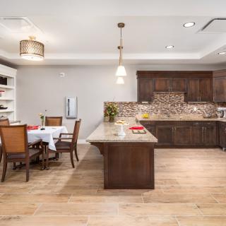 A modern kitchen with a wooden dining area, featuring a central island and elegant pendant lighting.