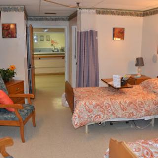 A cozy patient room in a healthcare facility, featuring two beds and comfortable seating.