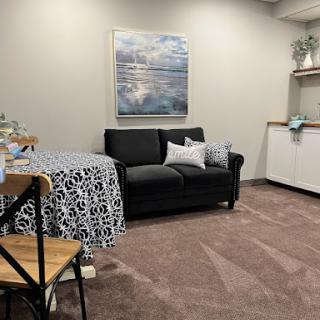 A cozy and modern living room setup featuring a black sofa, decorative pillows, and abstract artwork.