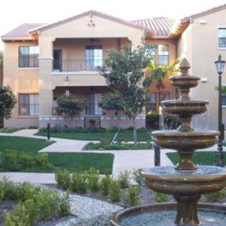 A well-landscaped apartment complex with a prominent fountain and pathways.