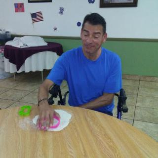 A man sitting in a wheelchair, engaged in an activity at a table.